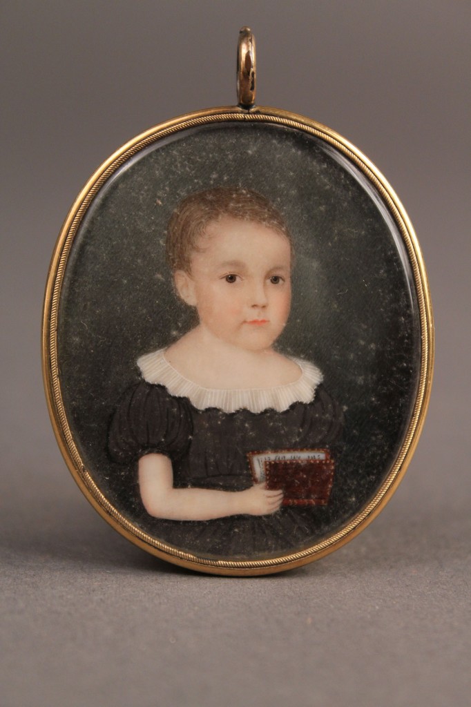 Lot 139: Portrait miniature of child with book, American School